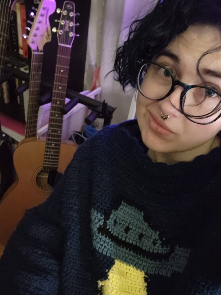 It's me, in a UFO sweater with some of my guitars in the background.